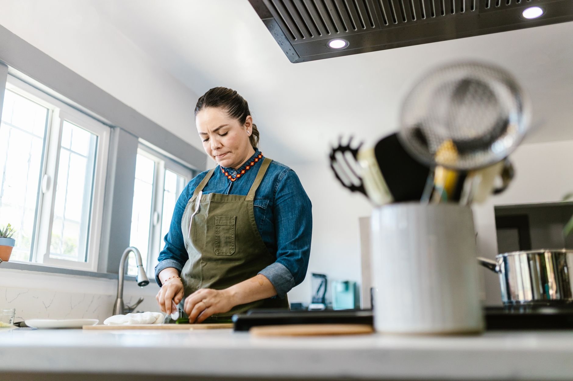 A woman in a domestic kitchen focused on chopping vegetables, creating a warm culinary atmosphere