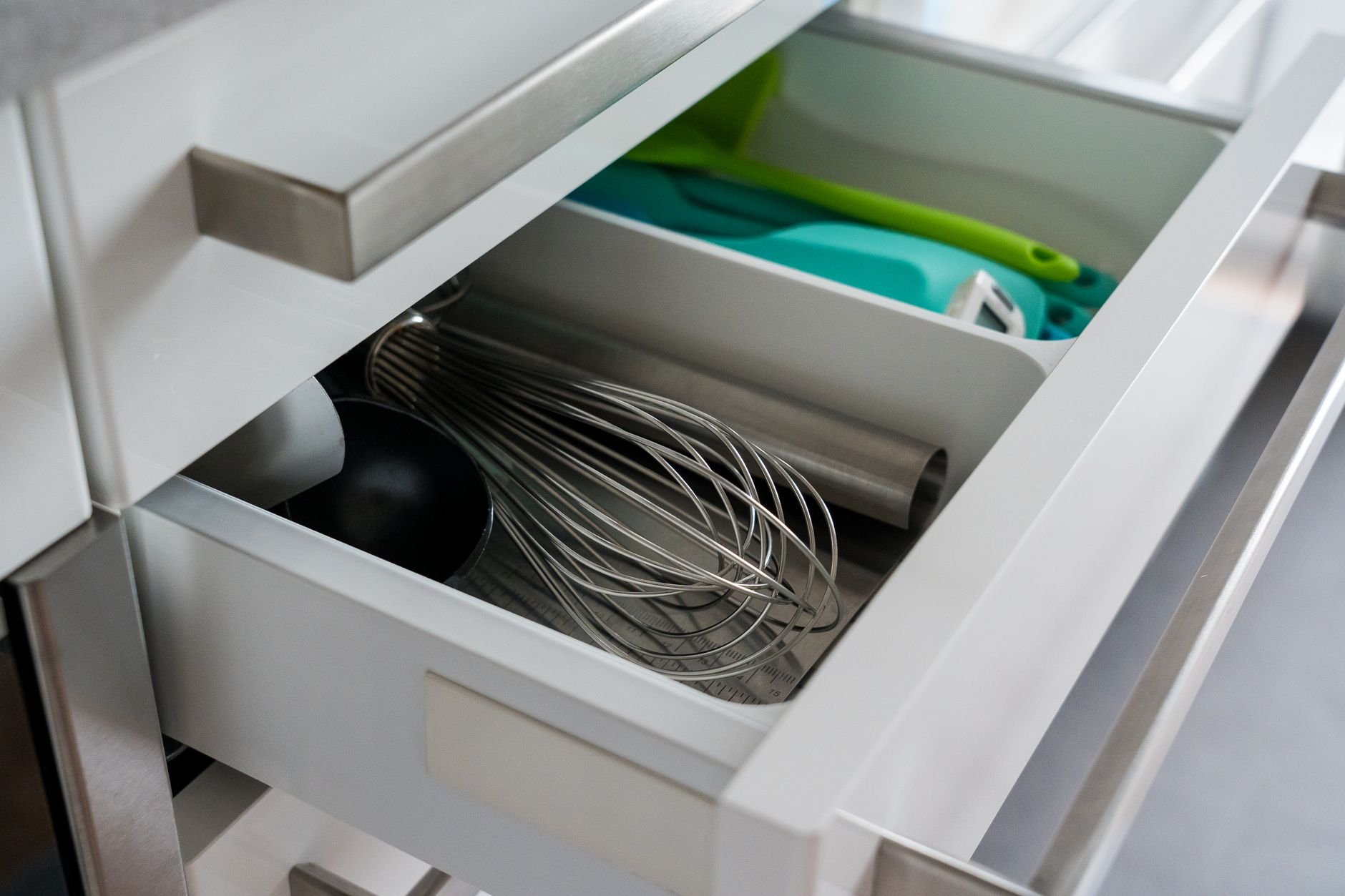 Open kitchen drawer showcasing organized utensils including a whisk and scoop