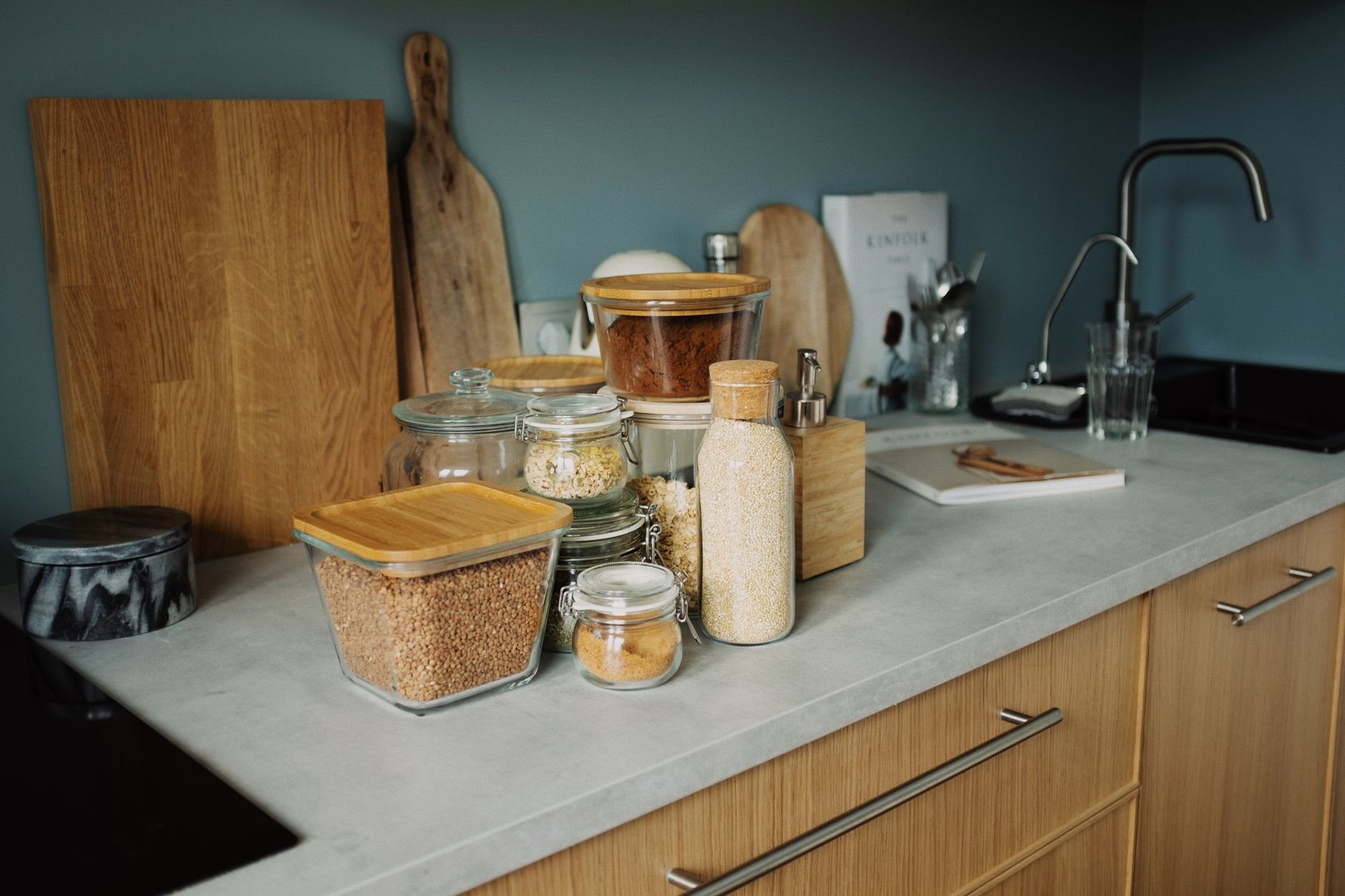 A minimalist kitchen setup features neatly arranged glass jars and wooden kitchenware on a contemporary countertop