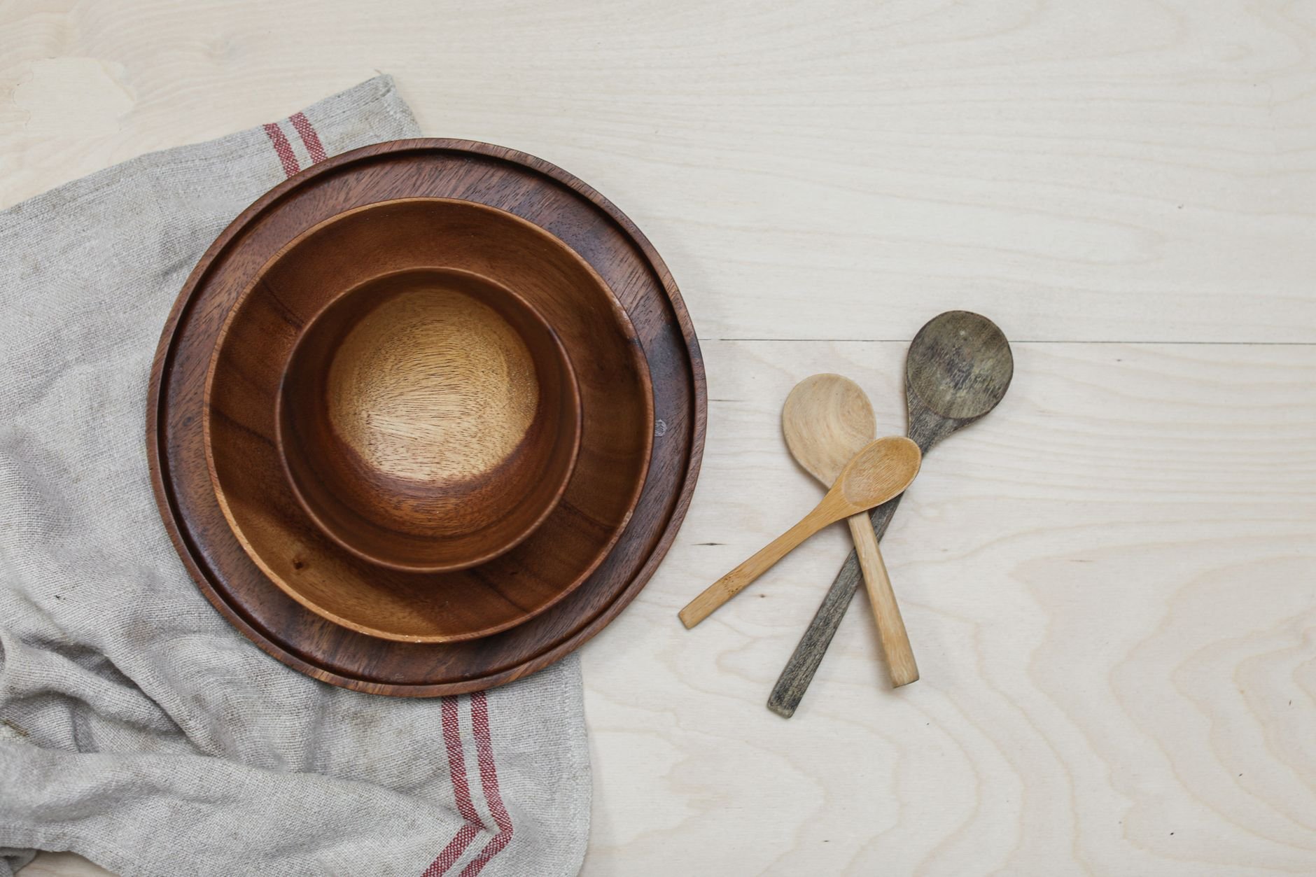 Close-up of rustic wooden bowls and spoons on a kitchen table with a linen cloth